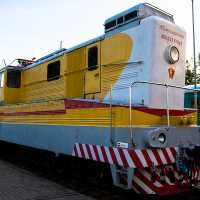 A train from the museum, colorfully adorned in yellow and white, resting on the tracks.