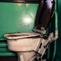 A train museum exhibit featuring a toilet in a room with green walls.