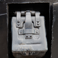 A metal box is sitting in a hole in the side of a train museum car.