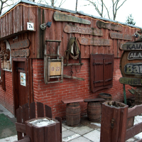 A rustic wooden pub exterior in Vilnius with traditional decor, featuring old barrels and signage in Latvian, suggesting a cozy spot for enjoying local brews.