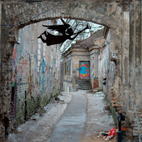 An arched entrance leads to a narrow, cobblestoned alley in Vilnius, adorned with vibrant graffiti, providing a contrast to the weathered walls and a glimpse of urban street art culture