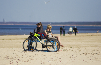 Two People Riding A Bike At The Beach.