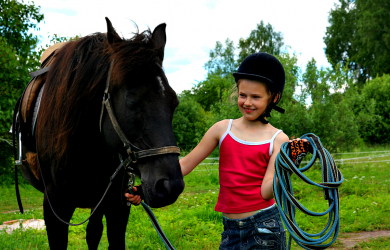 A Little Jockey Standing Next To A Horse.