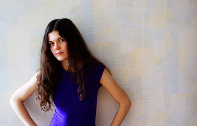 A Woman In A Violet Dress Leaning Against A Wall.