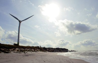 A Wind Turbine Harnessing The Power Of Wind On A Beach.